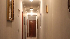 Un pasillo con alfombra estampada, cuadros en las paredes y un radiador a la izquierda.
