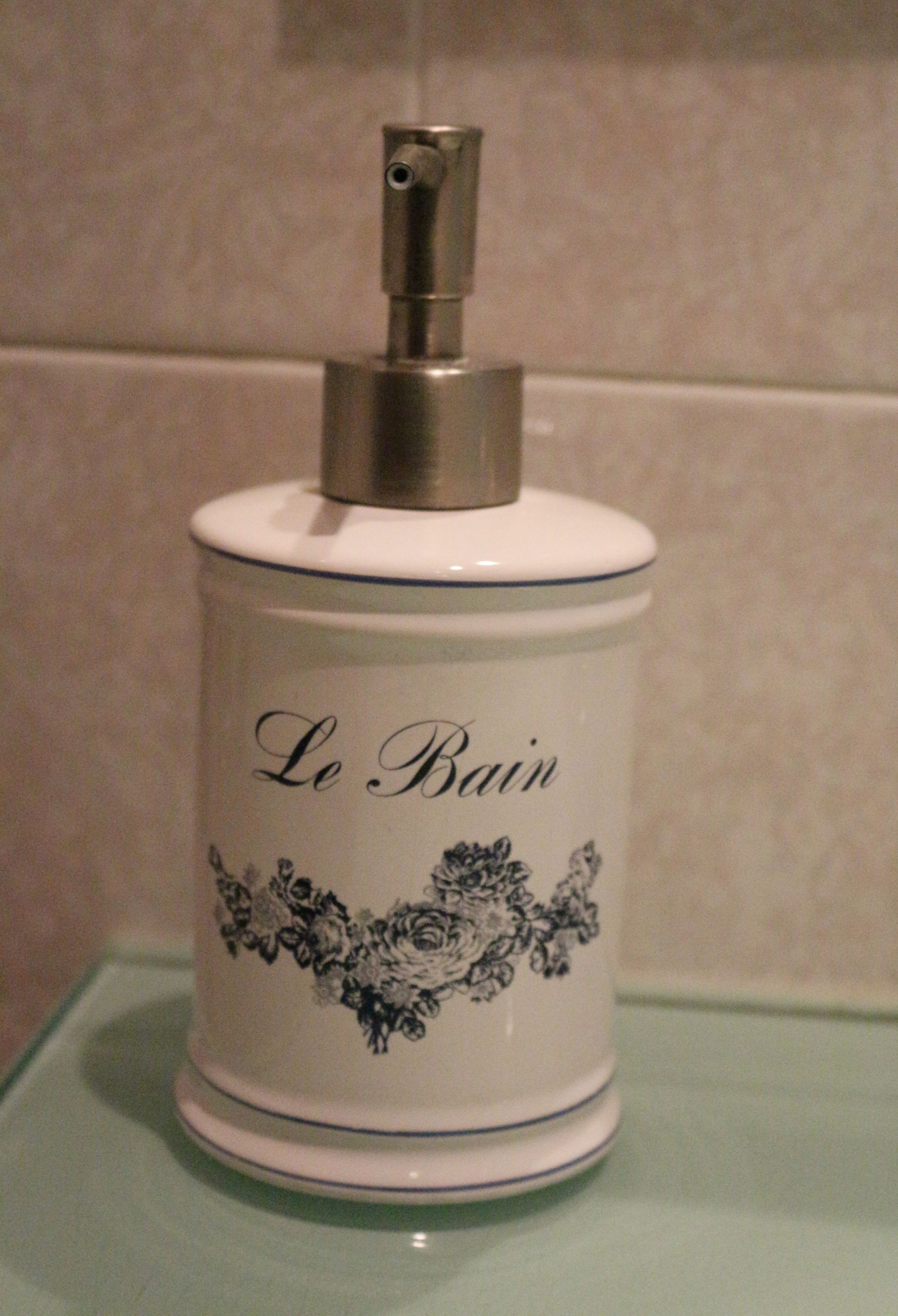 A bathroom with a white ceramic container labeled "Le Bain" with a floral design.