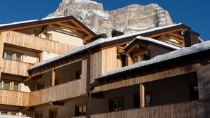 A multi-story wooden building with balconies, set against a backdrop of a snow-covered mountain. - Residence Civetta (Val di Zoldo)