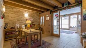 A wooden interior with a dining table, chairs, a lamp, and a rug. - Residence Civetta (Val di Zoldo)