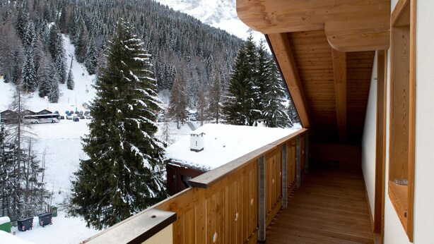 A wooden balcony with a view of a snowy mountain landscape and a ski lift. - Residence Civetta (Val di Zoldo)