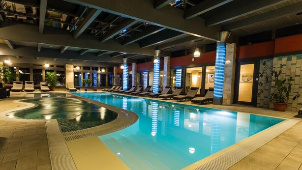 Una piscina interior con sillas de descanso y suelo de baldosas.