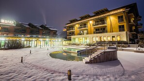 Un hotel con piscina, mobiliario exterior y una escalera que lleva a la entrada.
