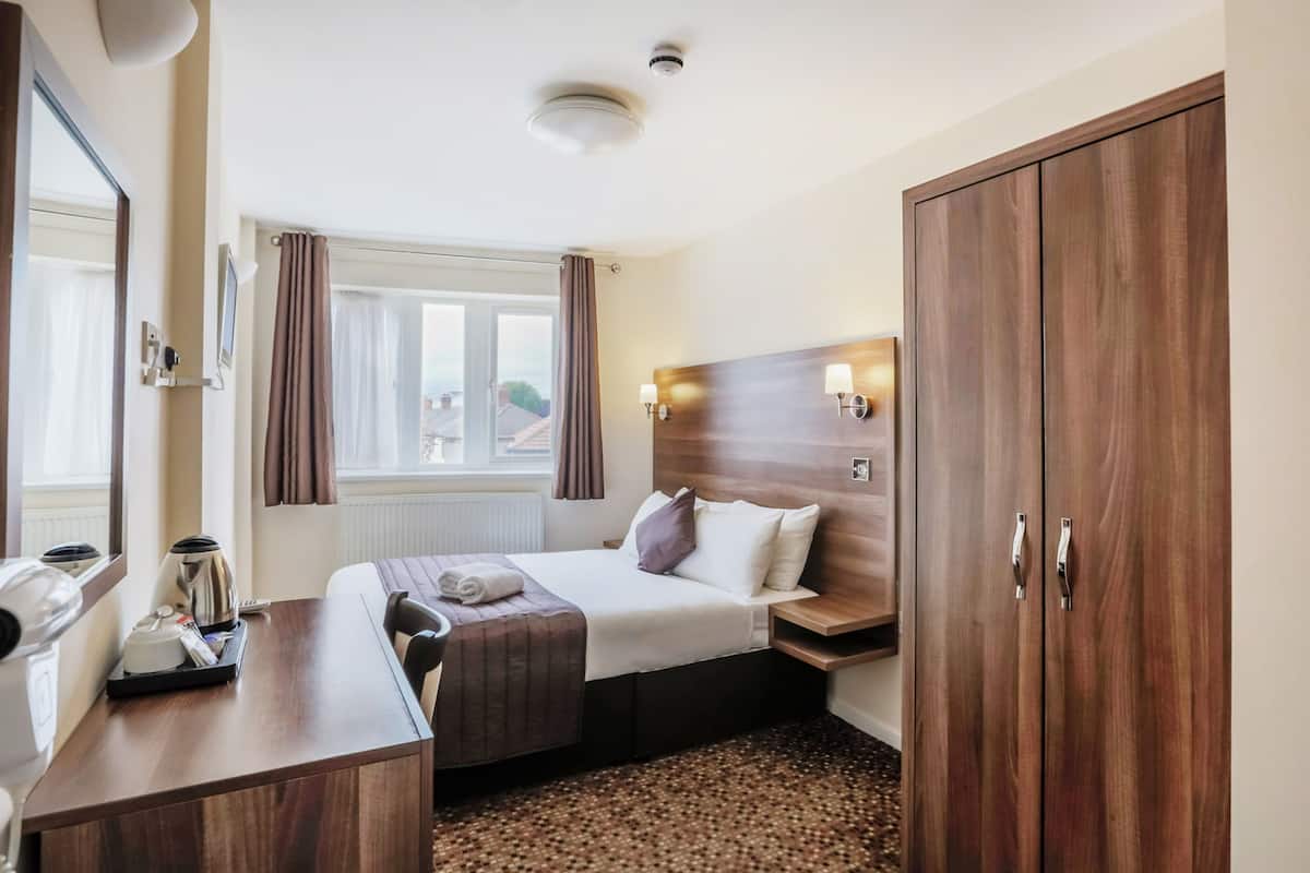Ett hotellrum med en säng, ett sängbord, en lampa och en garderob.
