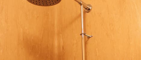 A shower with a handheld showerhead and a wall-mounted control panel.
