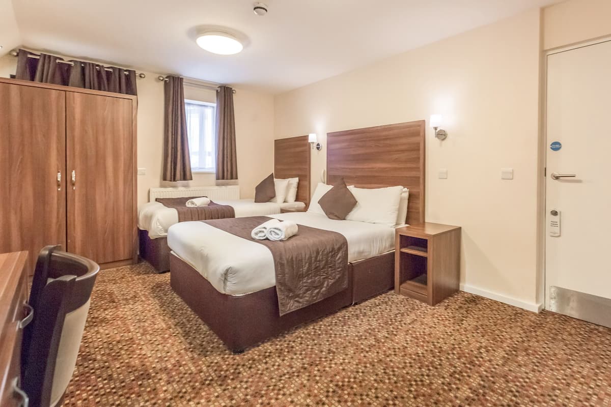 Ett hotellrum med två sängar, en garderob, ett skrivbord och ett golv täckt av matta.