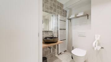 Ein modernes Badezimmer mit Waschbecken, Toilette, Handtuchhalter und Spiegel.