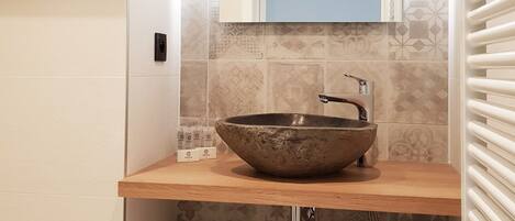 A bathroom with a wooden vanity, a large mirror, a vessel sink, and a towel rack.