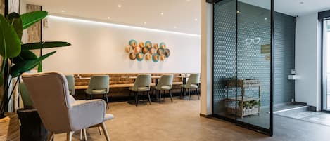 A modern interior with a seating area, a wall-mounted decorative piece, and a glass partition with a patterned design.
