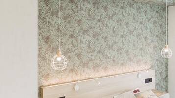 A bedroom with a large bed, two bedside tables, and a headboard with a leaf pattern.