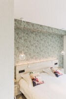 Un dormitorio con una cama grande, dos mesitas de noche y un cabecero con un diseño de hojas.