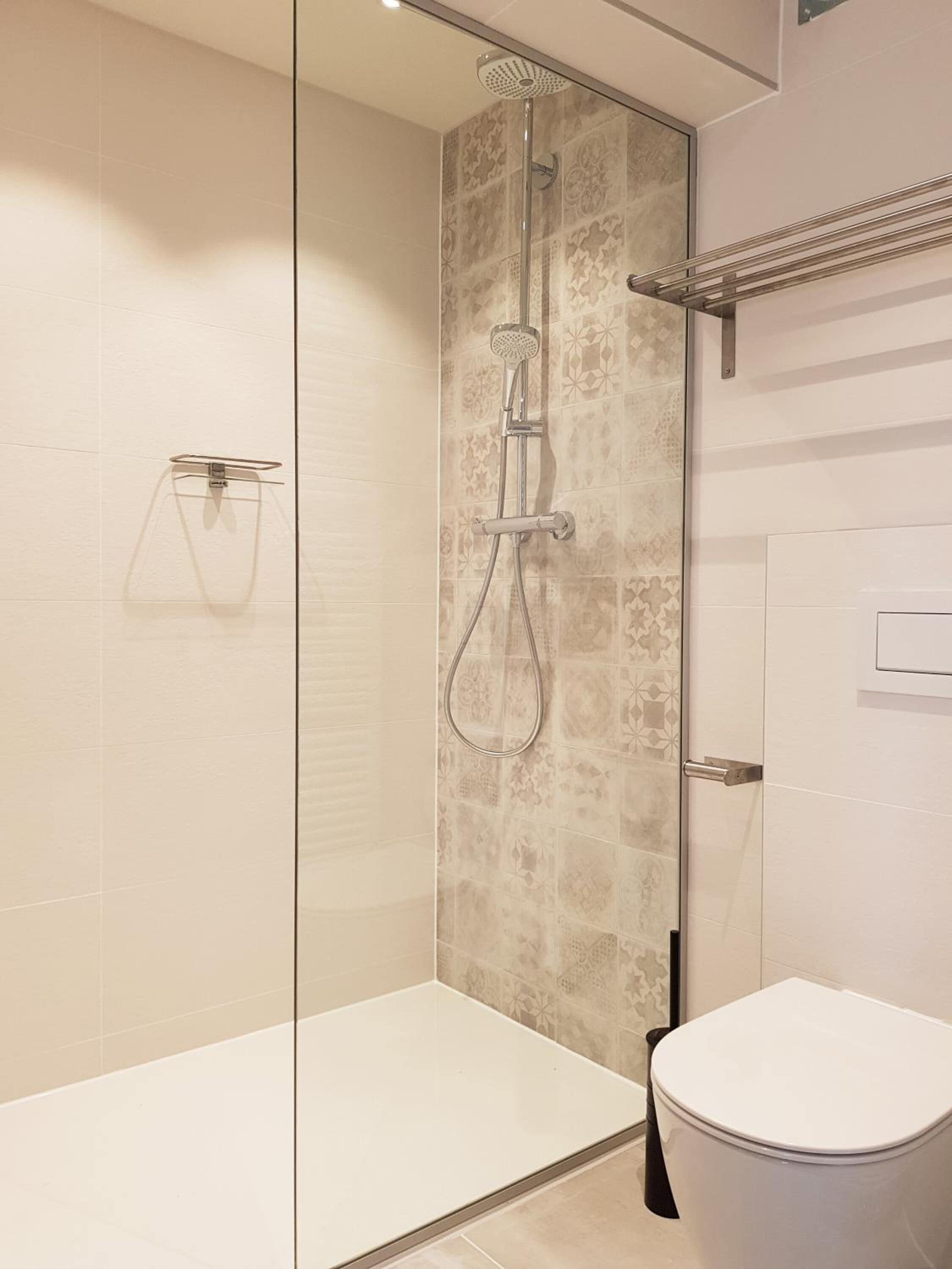 A modern bathroom with a glass-enclosed shower, a toilet, and a towel rack.