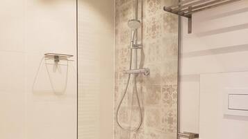 A modern bathroom with a glass-enclosed shower, a toilet, and a towel rack.