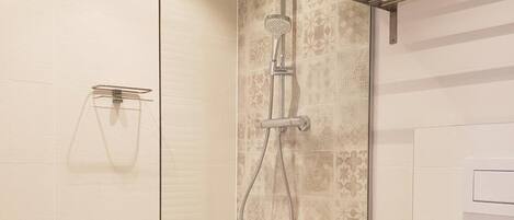 A modern bathroom with a glass-enclosed shower, a toilet, and a towel rack.