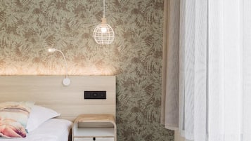 A bedroom with a bed, bedside table, and a wall with a leaf pattern.
