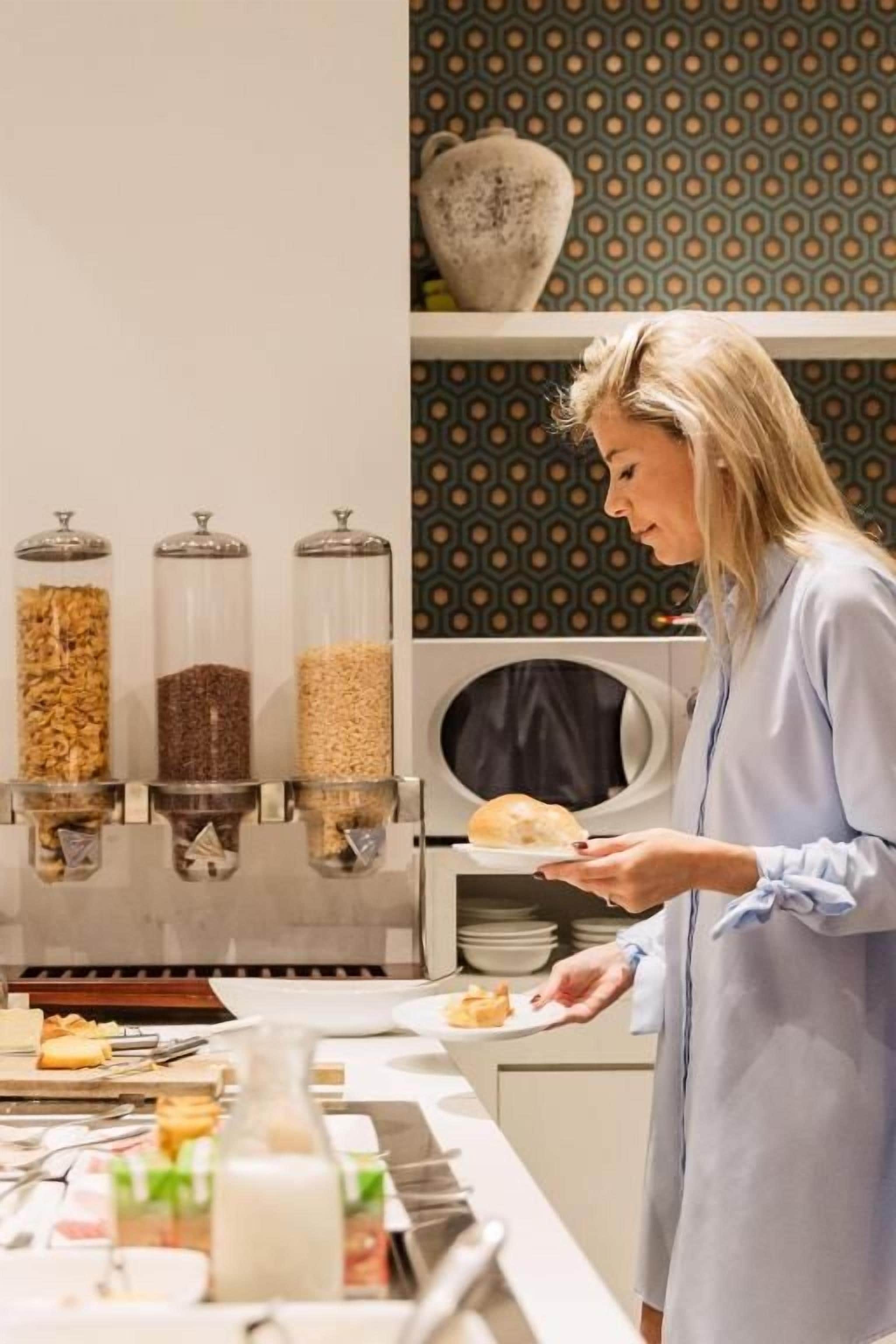 Una persona se sirve de un bufé con diversos alimentos y condimentos.