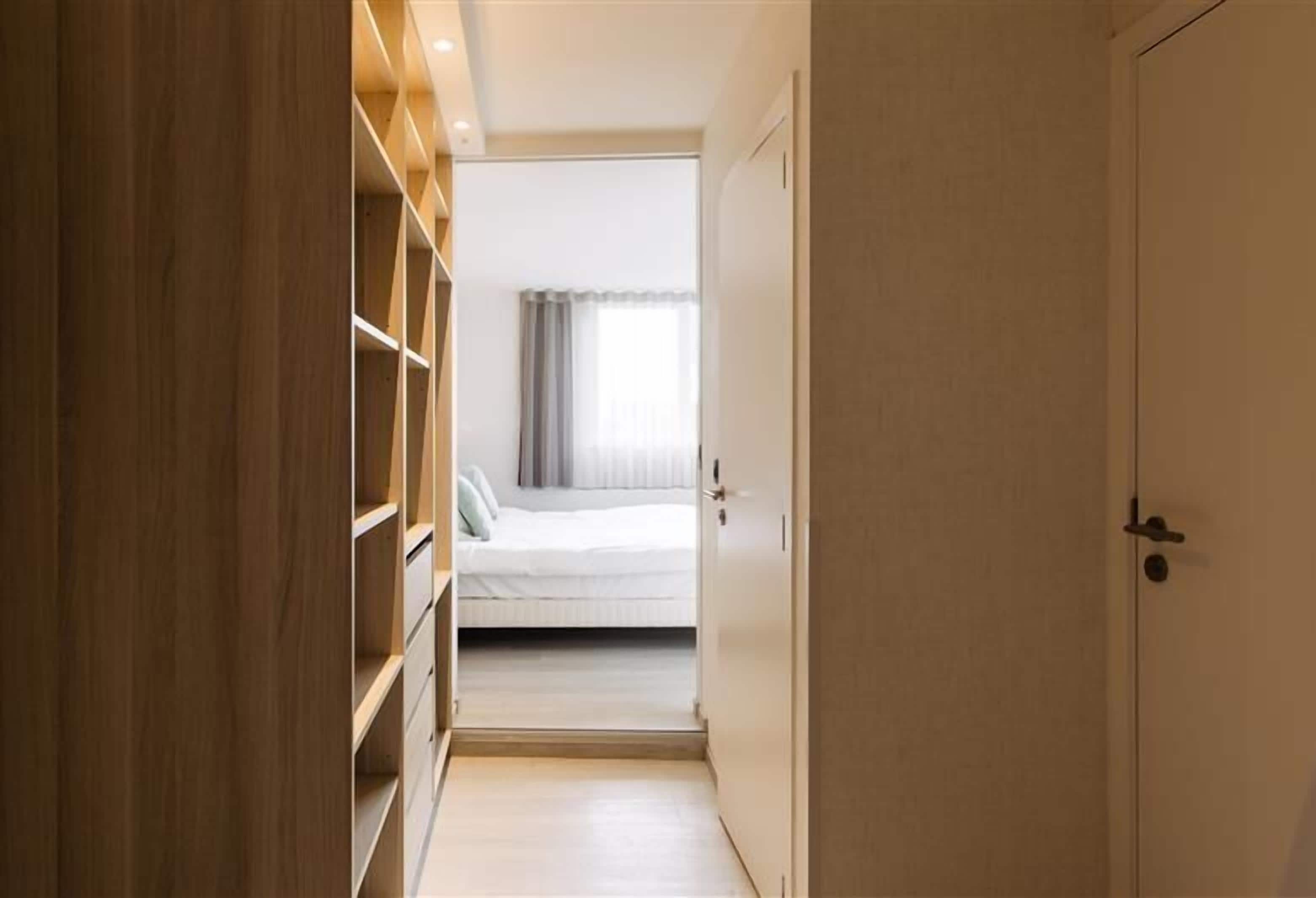 Ein schmaler Flur führt zu einem Schlafzimmer mit Bett und Kleiderschrank.