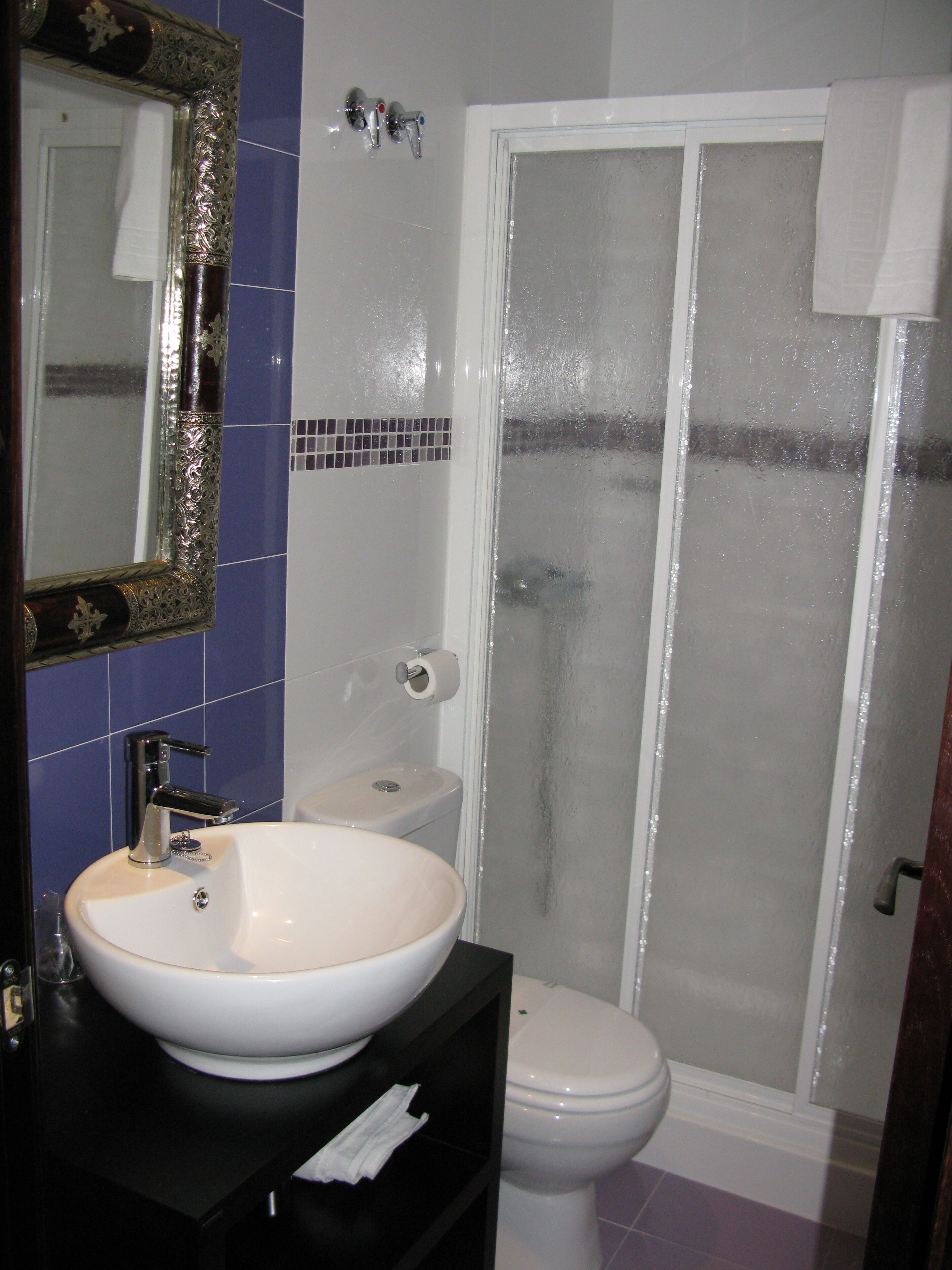 Un baño con lavamanos blanco, inodoro y cabina de ducha de vidrio.