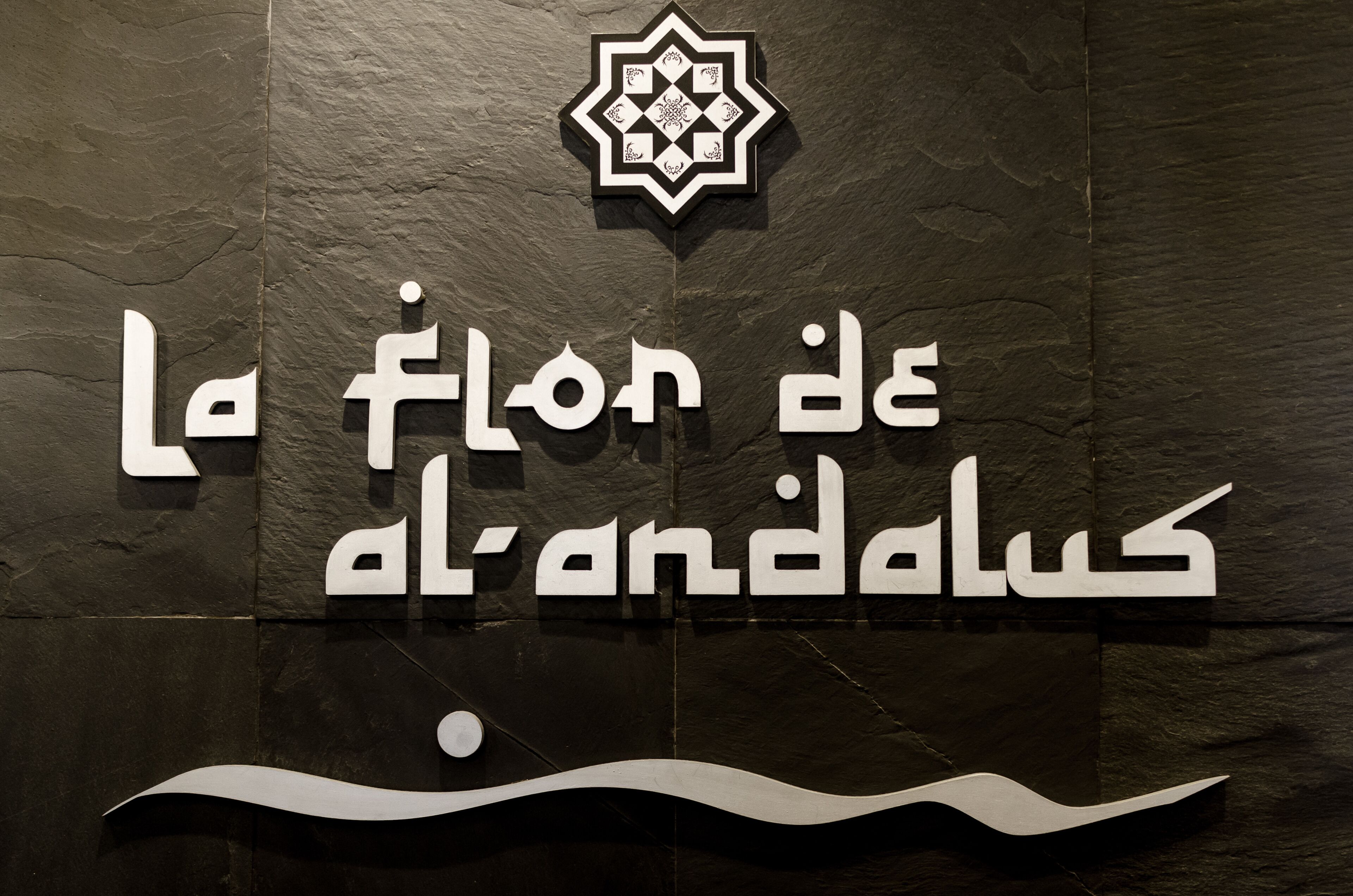 A sign with Arabic text and a geometric logo, likely indicating a hotel or establishment.