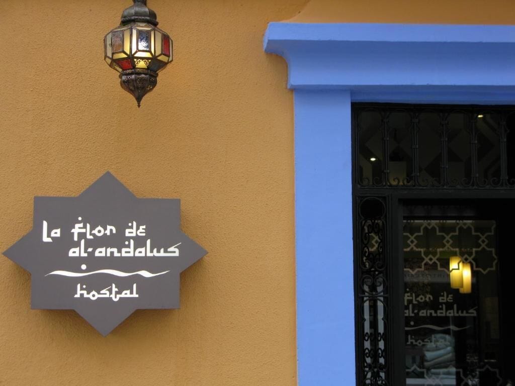 A sign with Arabic text on a building facade, a decorative street lamp, and a window with a patterned design.