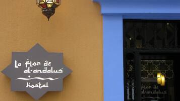 A sign with Arabic text on a building facade, a decorative street lamp, and a window with a patterned design.