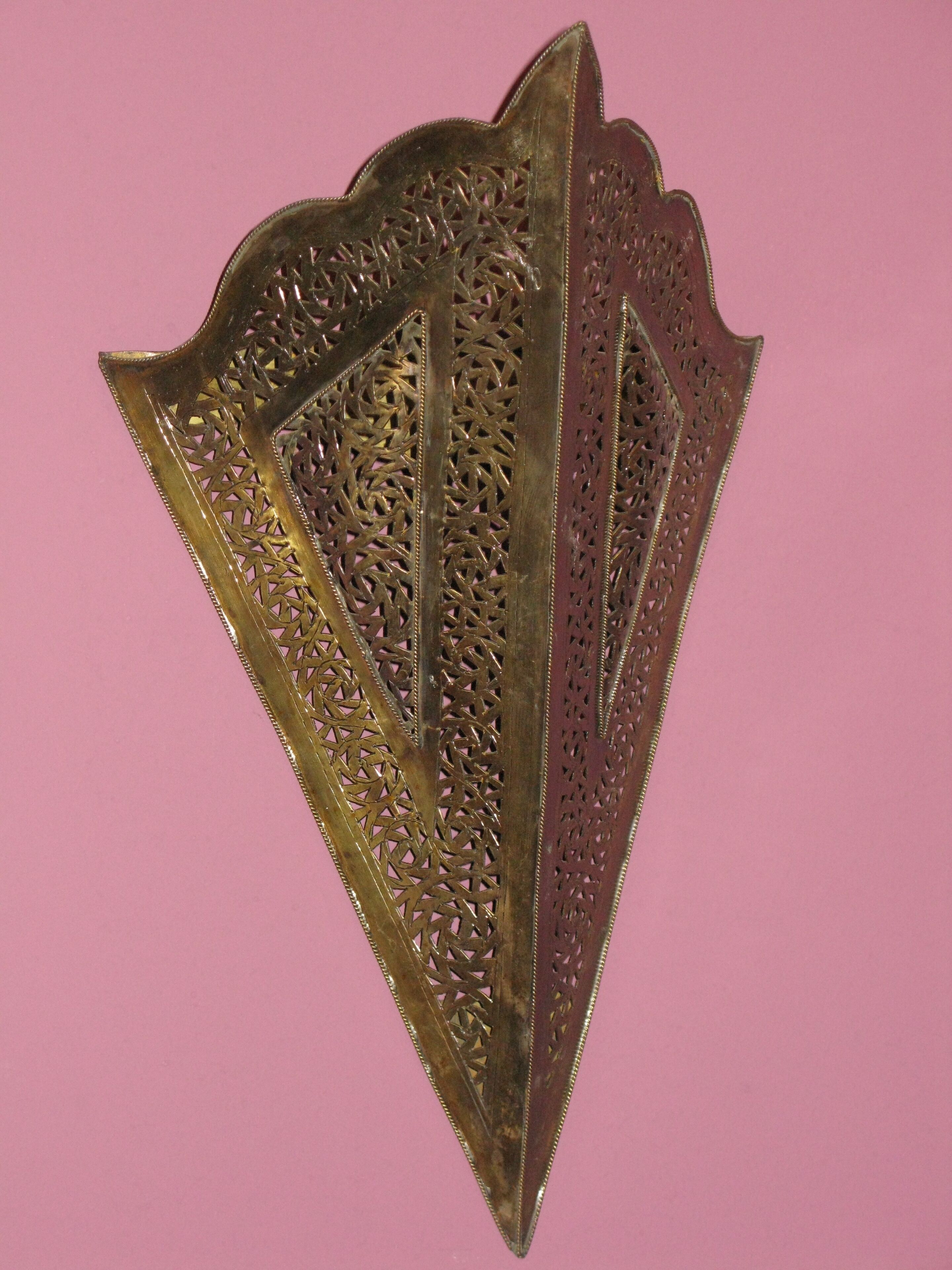 A decorative metal piece with intricate patterns and a pointed shape.