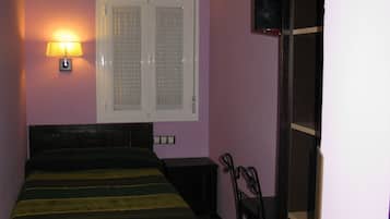 Un dormitorio con cama, mesita de noche, lámpara, ventana y puerta.
