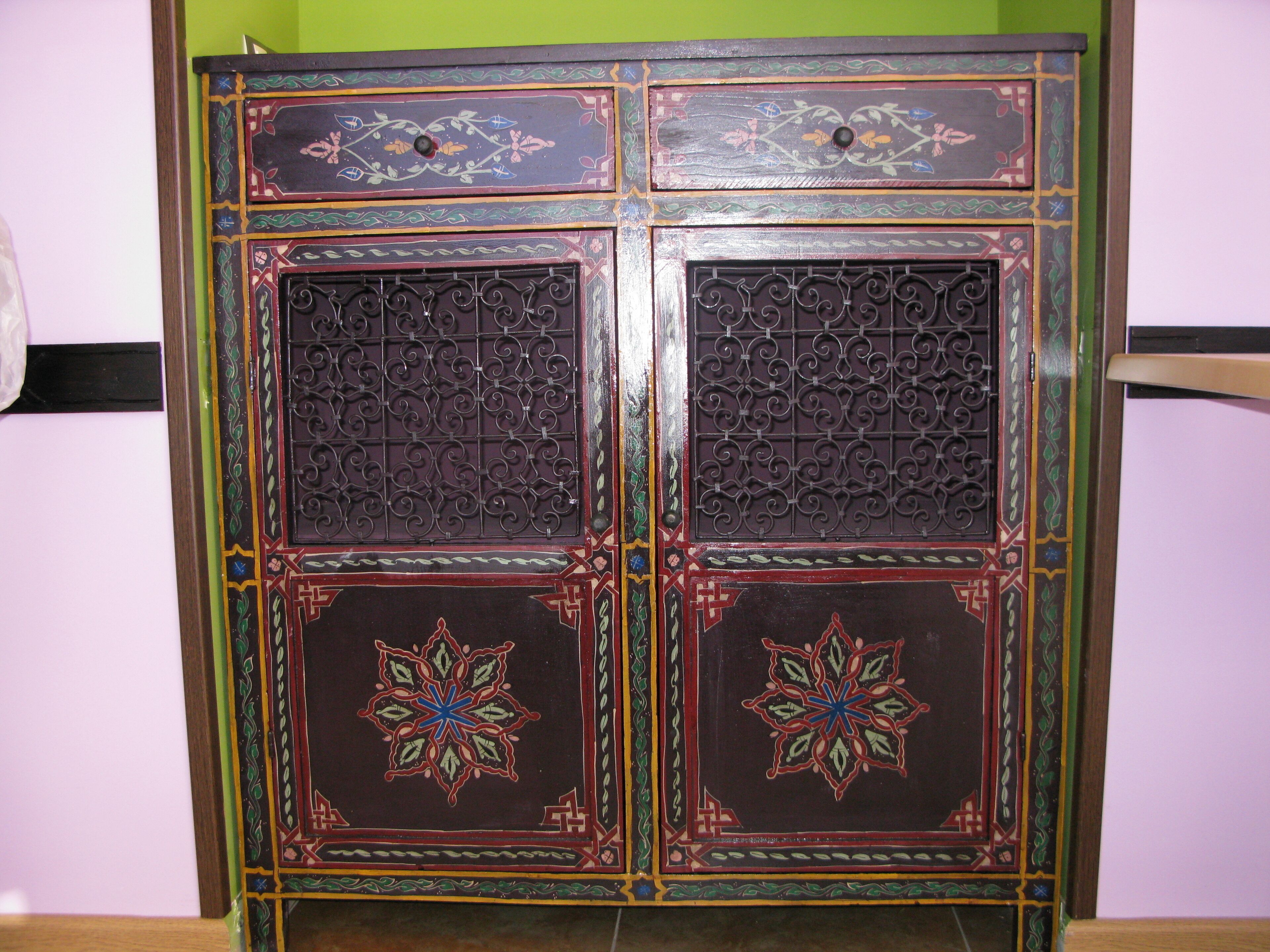Un mueble de madera tradicional con detalles metálicos elaborados y motivos coloridos.