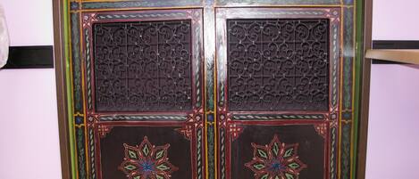 Un mueble de madera tradicional con detalles metálicos elaborados y motivos coloridos.