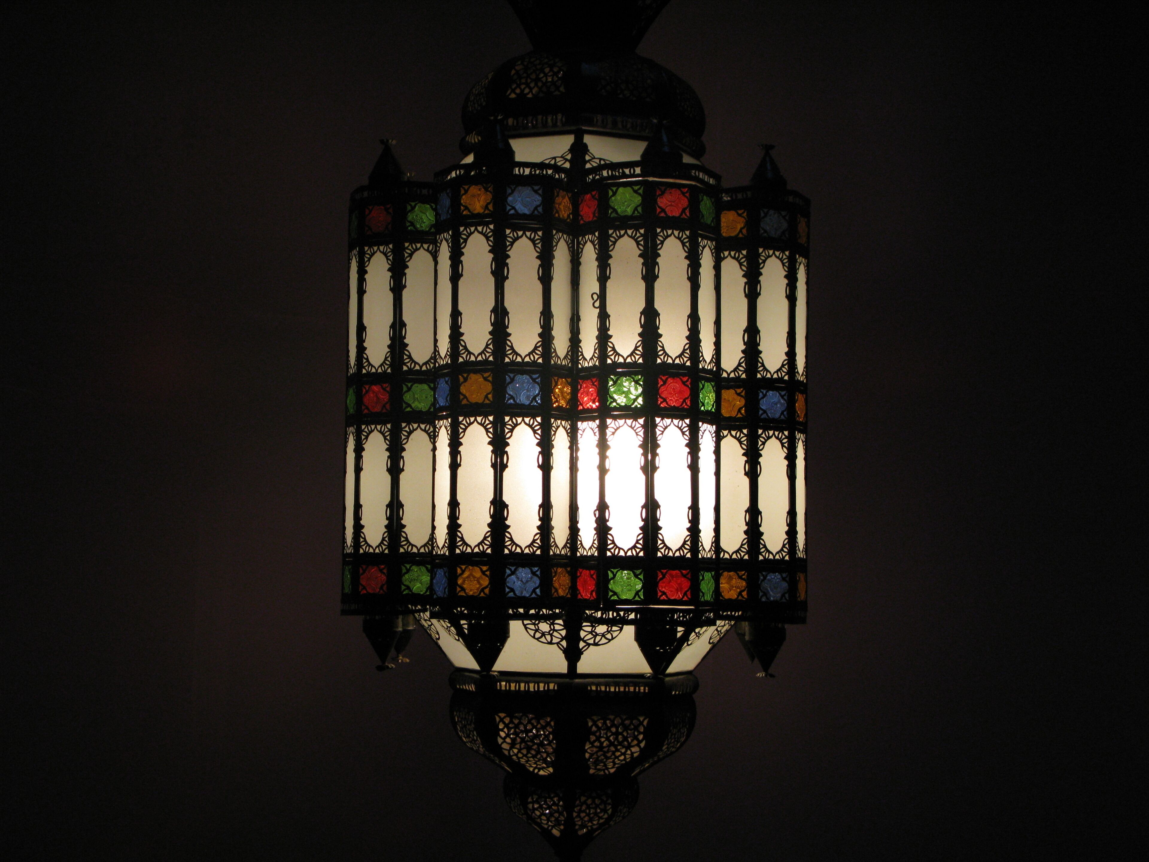 Une lanterne décorative ornée de motifs métalliques complexes et de panneaux de vitrail.