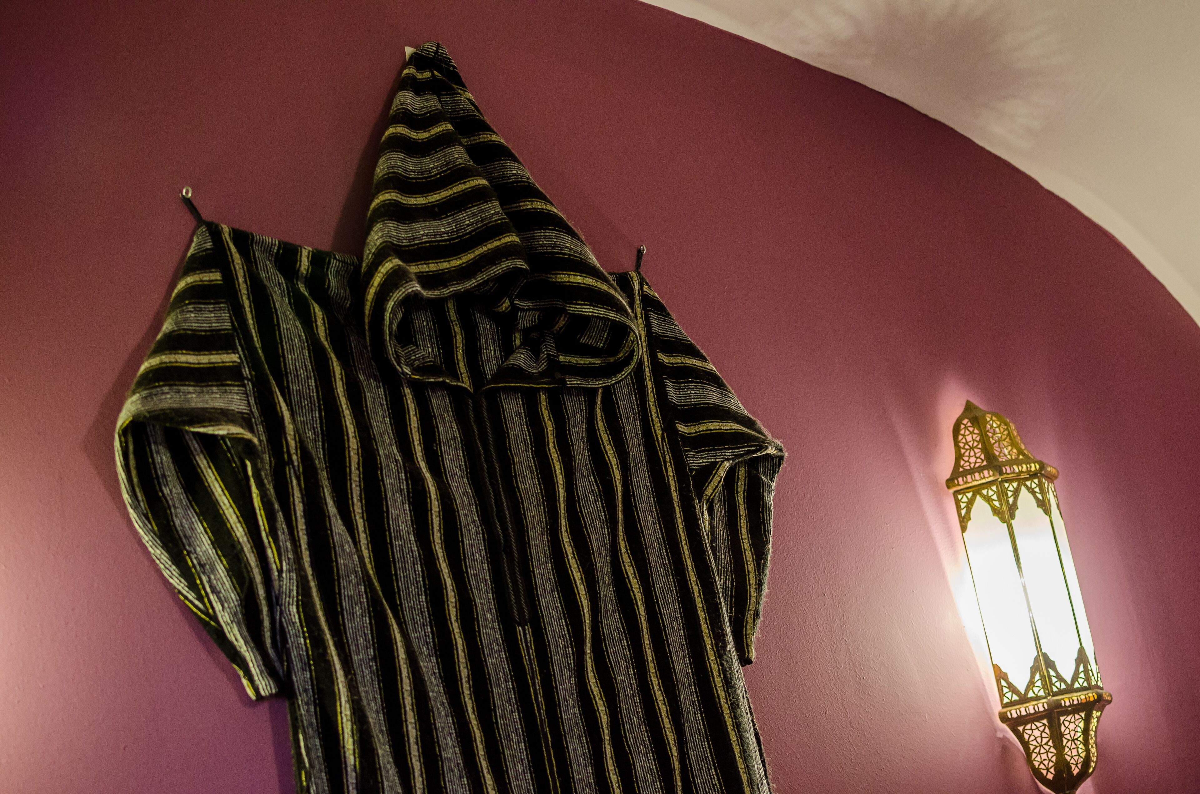 A striped fabric draped over a wall, a wall-mounted light fixture, and a curved ceiling.