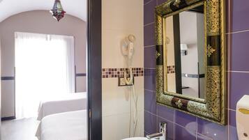 A bathroom with a white sink, a mirror with an ornate frame, and purple tiles on the walls.