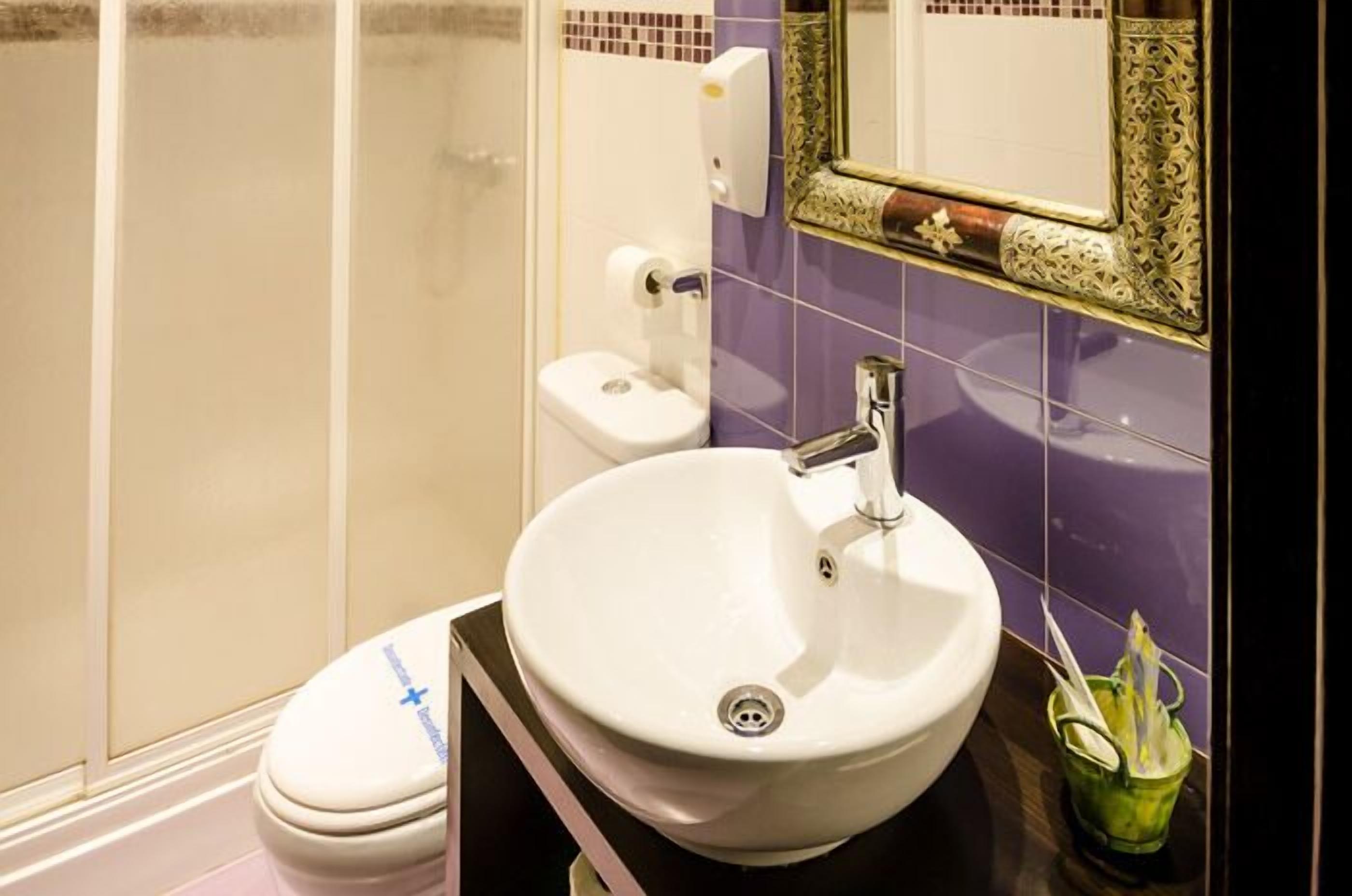 A bathroom with a white sink, a toilet, and a shower area.