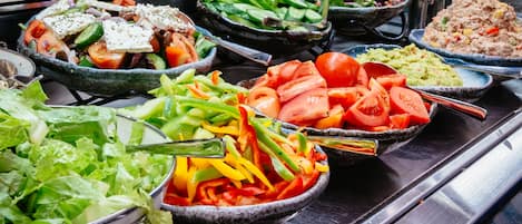 A buffet with various dishes including salads, vegetables, and a meat dish.
