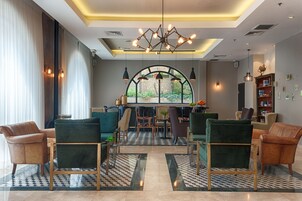 Un área de descanso moderna con sofás de cuero, una mesa central y un ventanal arqueado único con vistas a la vegetación.