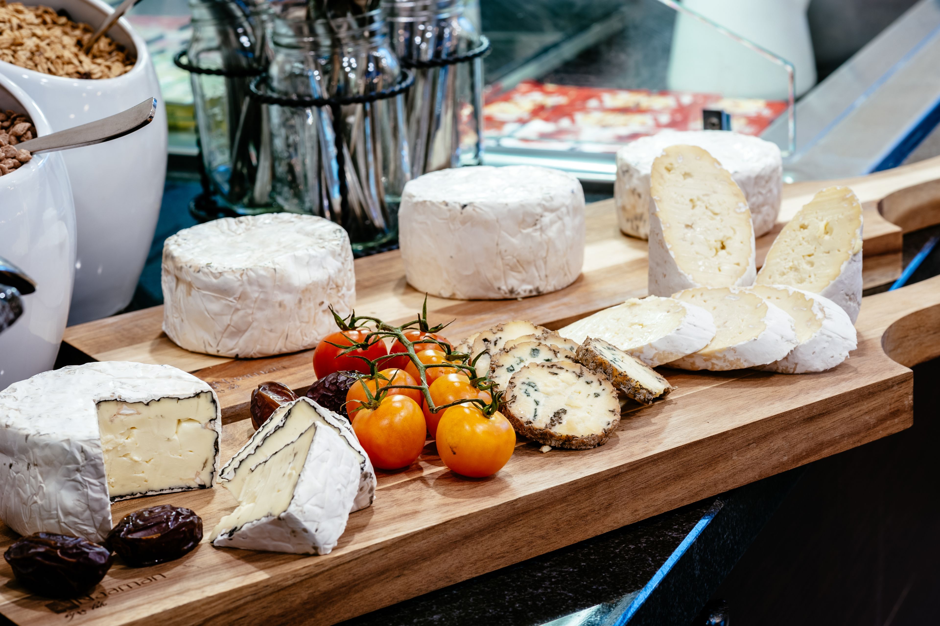 A variety of cheeses and tomatoes on a wooden board.