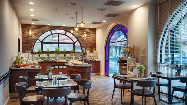 A restaurant with a brick wall, large arched windows, and a central island with a bar. - The Eldan Hotel (Jerusalem)