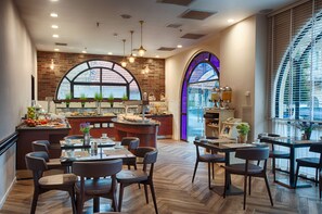 A restaurant with a brick wall, large arched windows, and a central island with a bar. - The Eldan Hotel (Jerusalem)