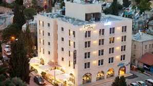 A multi-story hotel with a rooftop terrace, multiple balconies, and a well-lit entrance. - The Eldan Hotel (Jerusalem)