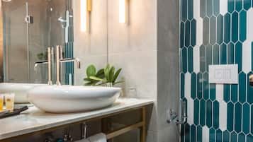 Un baño moderno con un lavamanos tipo recipiente, un inodoro y una zona de ducha.