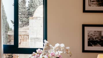 A room with a large window, a potted orchid, and framed pictures on the wall.
