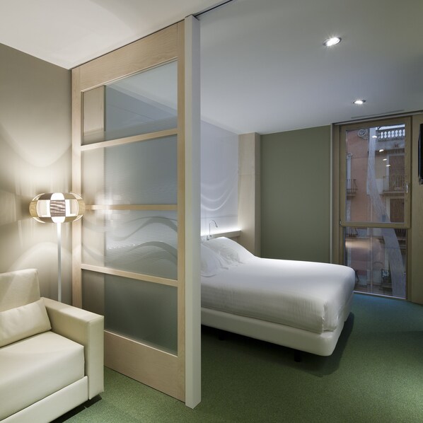 A modern bedroom with a bed, a chair, and a floor lamp.