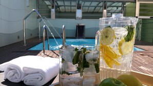 Escena junto a la piscina con un vaso de té helado, un vaso de agua y una toalla blanca enrollada.