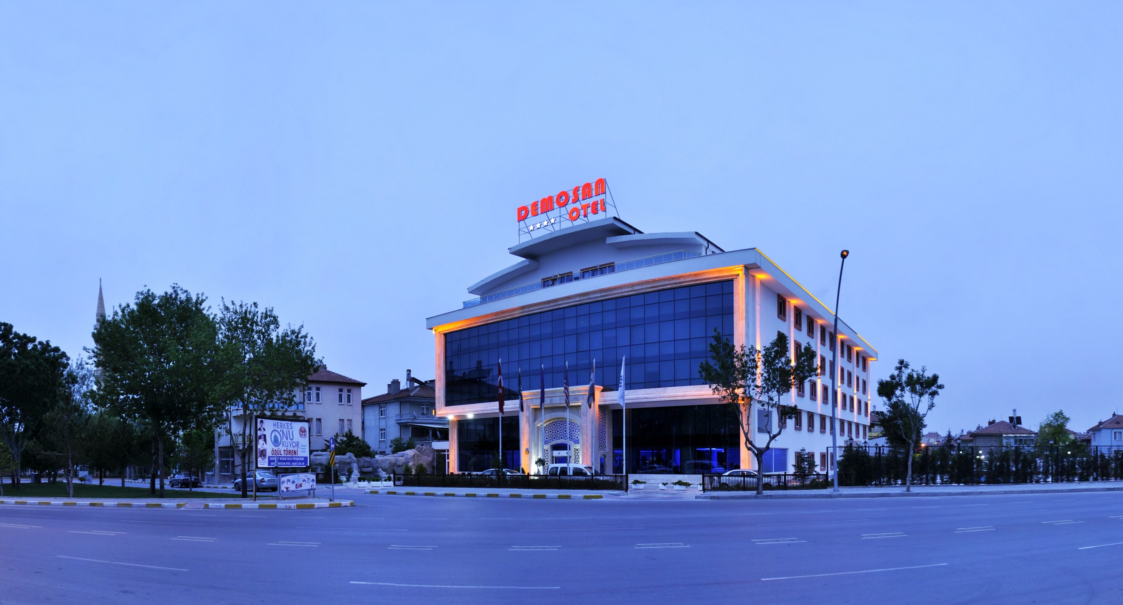 A modern hotel with a prominent sign, large windows, and a well-maintained parking area.