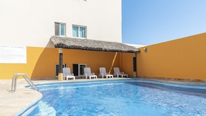 A swimming pool with a thatched roof and lounge chairs. - Hotel Gran Via (Veracruz)