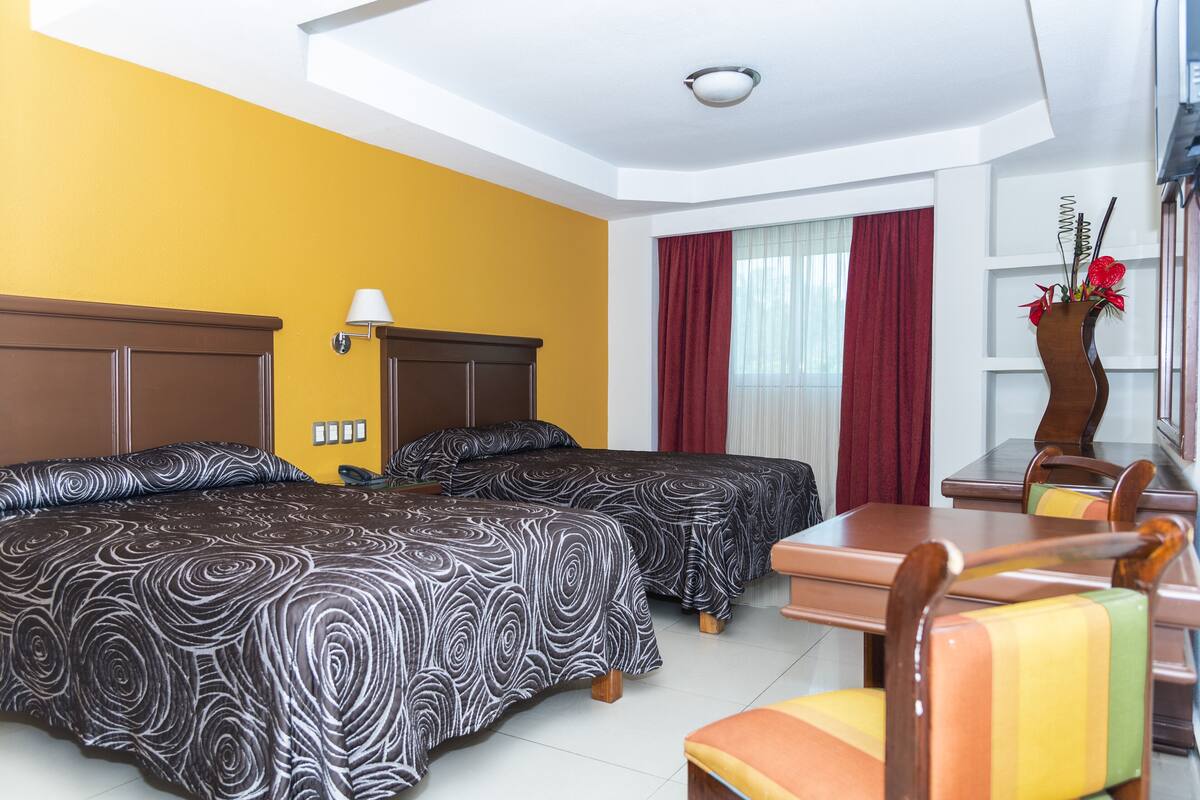 A hotel room with two beds, a dining table, and a chair.