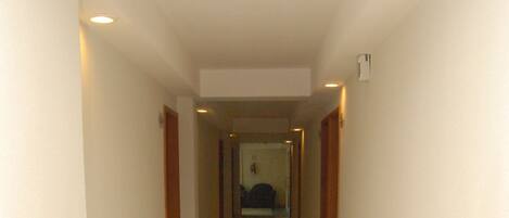 Un pasillo con piso de baldosas y paredes, que conduce a una habitación con cama.