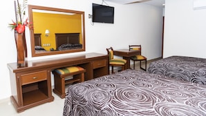 A hotel room with a bed, a desk with a chair, a TV mounted on the wall, and a mirror. - Hotel Gran Via (Veracruz)