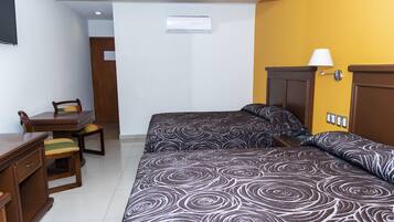 Una habitación de hotel con dos camas, un escritorio, una silla y una lámpara.