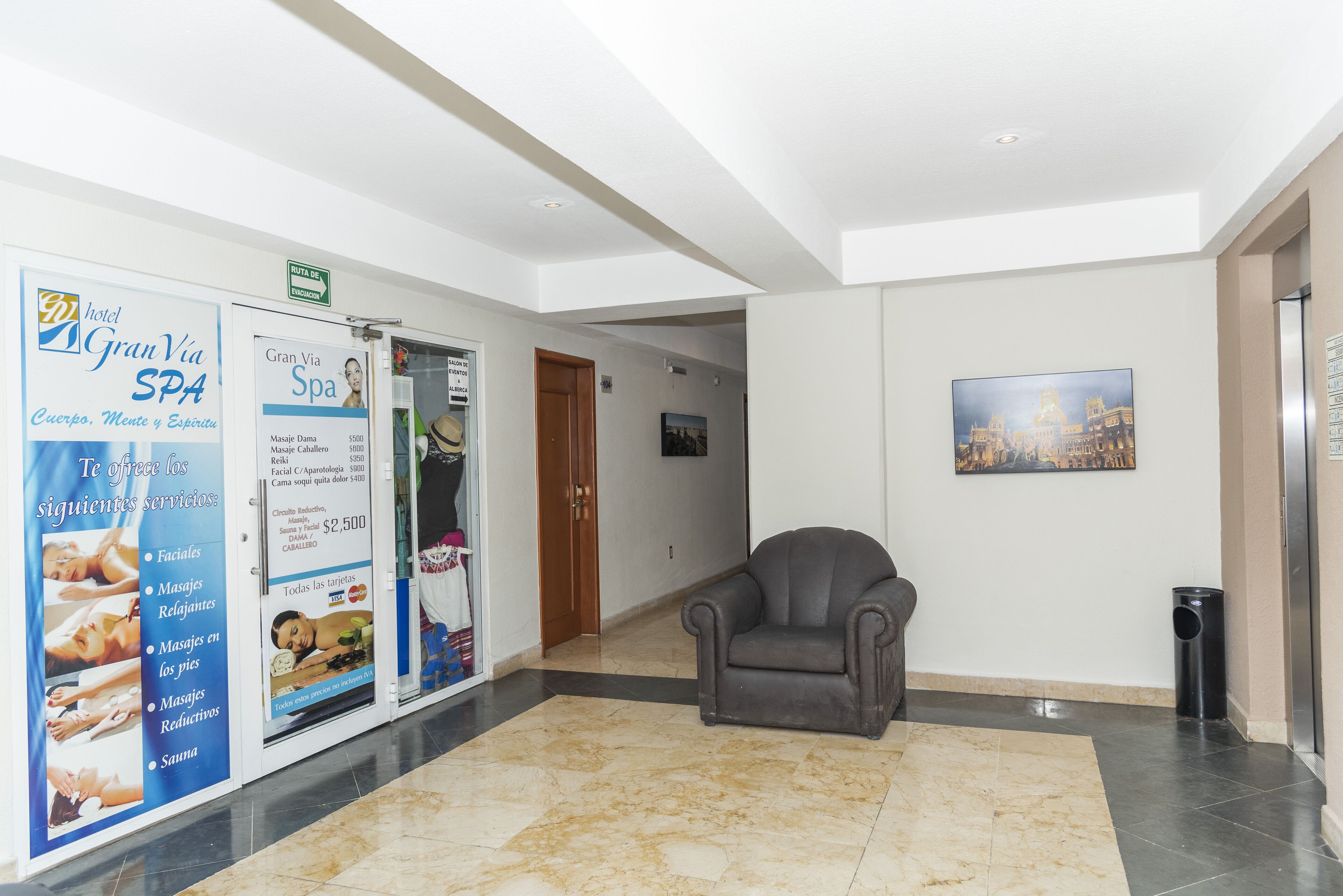 A hotel lobby with a marble floor, a leather armchair, and a spa advertisement on the wall.
